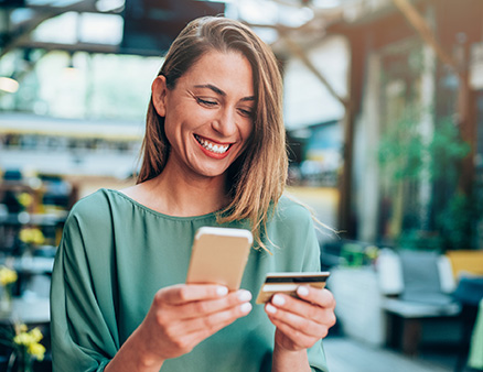 Young woman paying with debit card online using her phone.