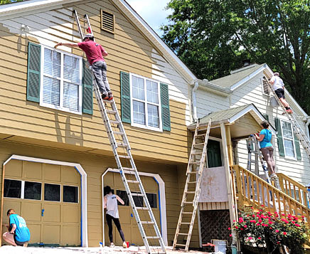 Group of workers painting exterior of house.