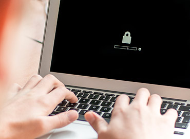 Person typing on laptop, secure lock shown on screen.