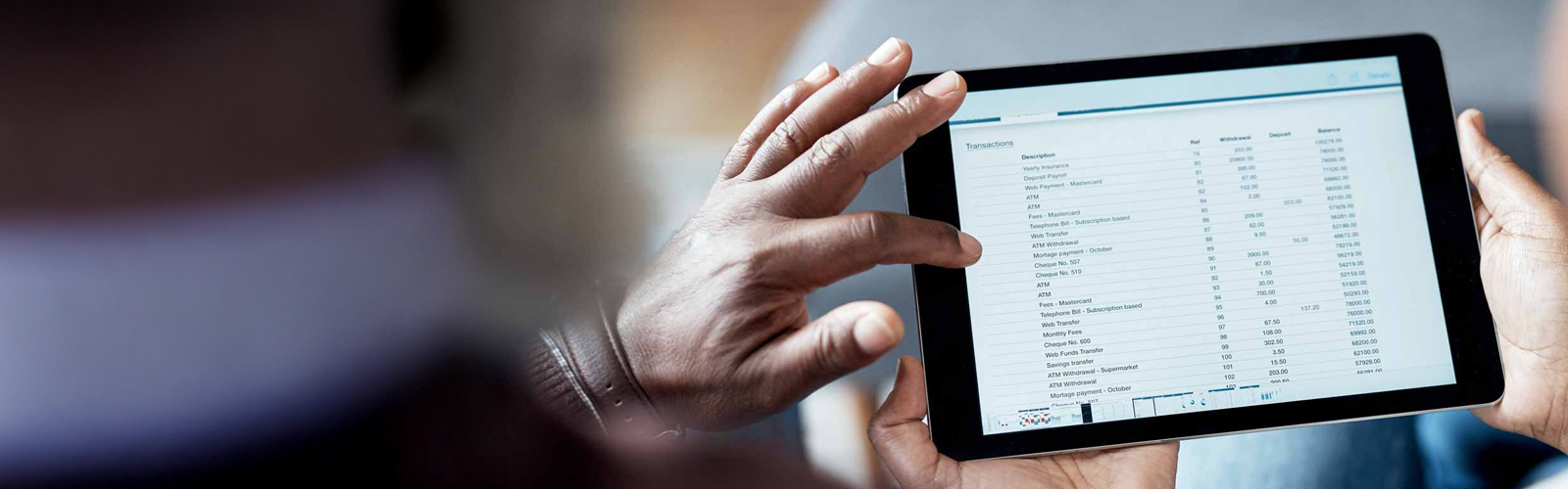 A closeup of a tablet screen displaying a monthly statement being viewed by a couple.