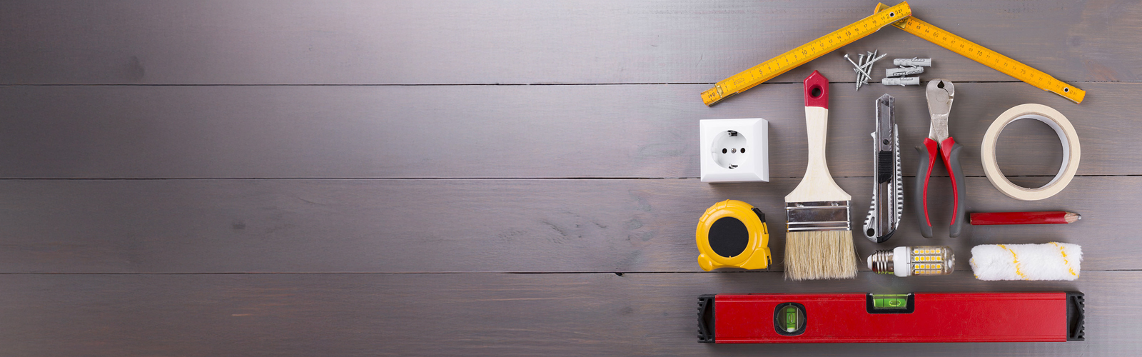 A conceptual photo of various tools like a paint brush, level, tape measure, wrench, etc. all in the shape of a house.