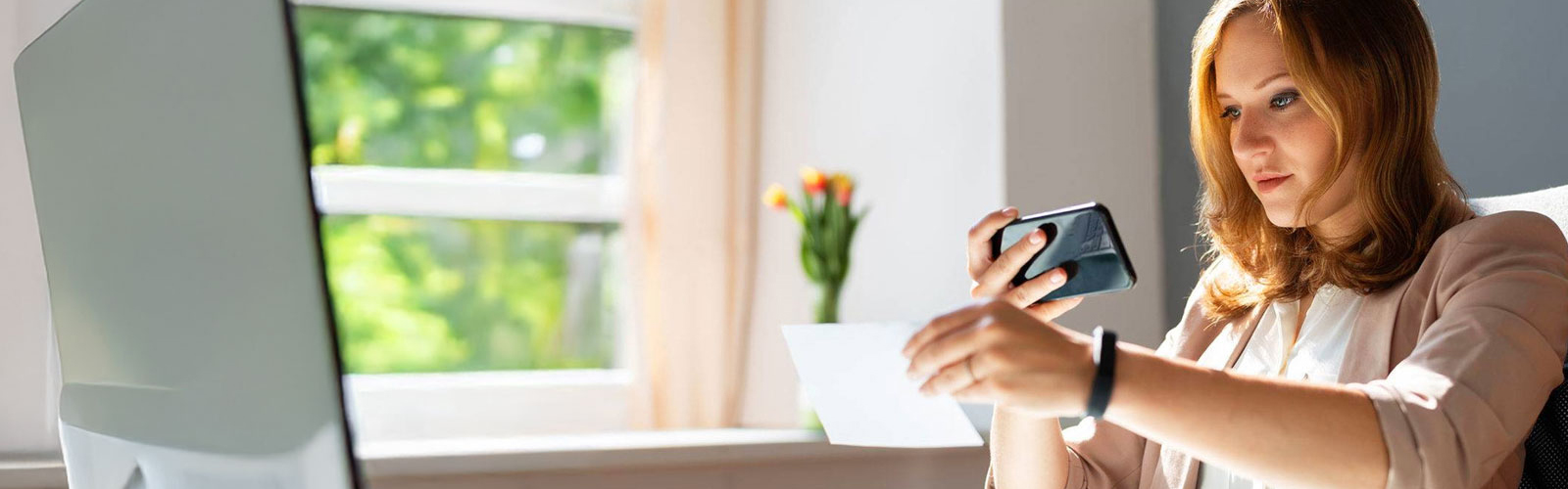 A woman taking a photo of a check with her cell phone.
