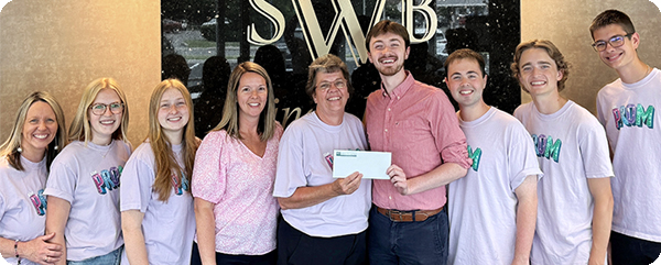 The members of Stage Notes receive a check and pose for a donation photo at WSB.