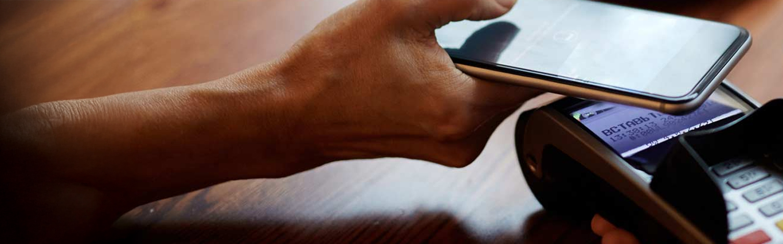 close up of a person using their phone to make a payment on a card terminal.