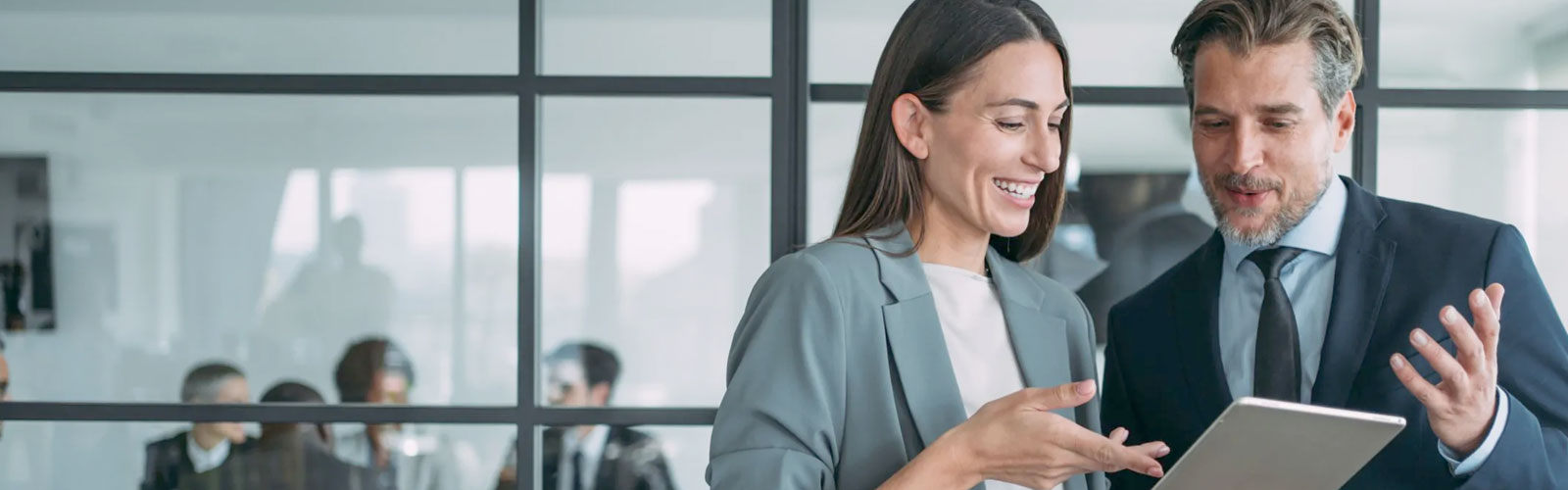 A business man and woman in an office going over a digital statement.