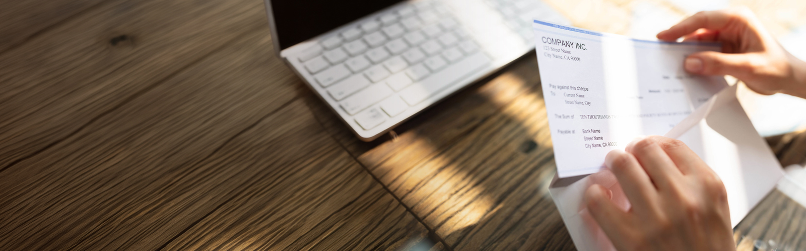 A person opening an envelope containing a fraudulent check.