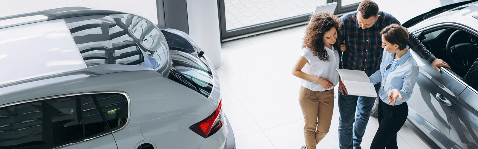 A couple in a car dealership going over terms with a car salesperson.